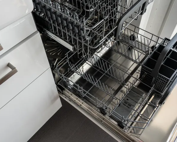 Open stainless steel dishwasher with its upper and lower racks pulled out