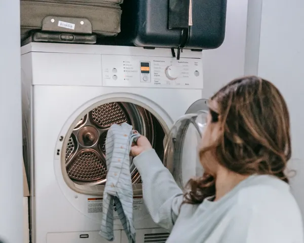 Homeowner taking clothes out of a stacked front-load dryer in a home laundry room