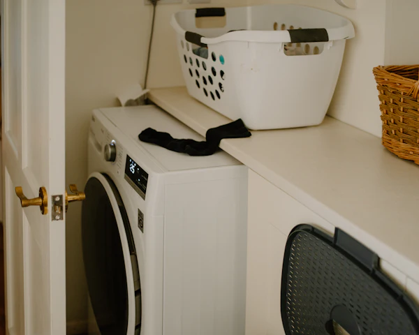White front-load washer in a home laundry room with a laundry basket on the counter above